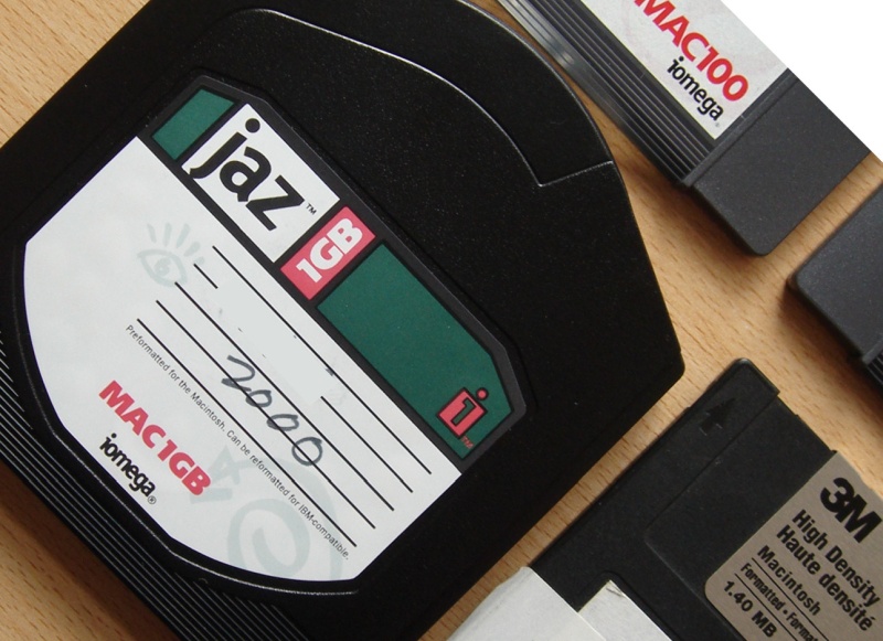 An Iomega Jaz disk pictured at a 45 degree angle with some other Jaz and floppy disks. The disks were ready for recovering data in our lab.