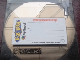 A Syquest 135mb Ez-Drive disk is shown in the picture. The label indicates 135mb Removable Cartridge and the name Syquest is embossed on the cartridge.